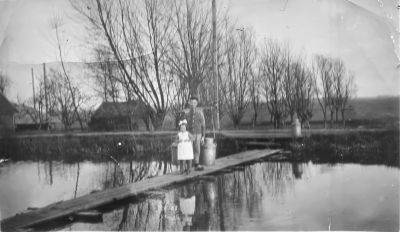 Het vlot over de Bijlmer Ringsloot
Werd gebruikt om met de fiets over de Ringsloot te komen. Ook de melk werd hier overgezet. Aan de overkant liep de verharde weg.
Op het vlot H. van Wijngaarden met dochter Matje.
