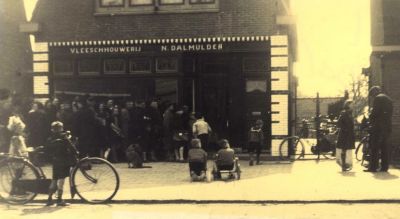 Slagerij Dalmulder
Nicolaas Dalmulder slager in Weesp opende een filiaal in Driemond met zoon Jan. Deze nam de zaak in 1946 over. De foto is gemaakt in de eerste jaren na de oorlog toen het vlees nog op de bon was en het aanbod soms mager, waardoor niet iedere klant vlees voor zijn of haar bonnen kon krijgen. Op de foto nog ‘N. Dalmulder’
Keywords: middenstand;slagerij;Dalmulder;Bletzstraat