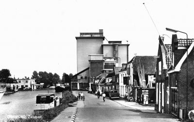 Otten, fabriek veevoeder en olie
±1966. Midden achter Otten. Verder aan her Zandpad: eerste huis rechts bakkerij Jan Smit, fietsenhandel/benzinepomp Van Schaik, timmerbedrijf De Groot, kruidenier Bleijenberg en kruidenier Jan Meester (net zichtbaar naast Otten).
Keywords: Geinbrug;Driemond;Otten,veevoeder;olie