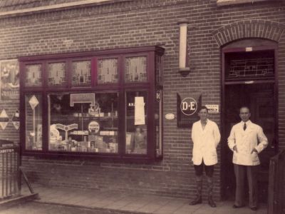 Kapper Zwart
Kapper Zwart (met assistent/leerling?) na de verbouw van zijn huis tot echte zaak in 1934. Voordien knipte hij in zijn woning. Er werden nu ook rookwaren verkocht (sigaren, sigaretten en pijpen)
Keywords: kapper;Zwart;Geinbrug;Driemond