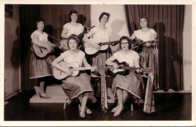 Zanggroep 'De Geriehetties
De groep bestond uit 6 boerendochters uit Weesperkarspel. De naam was samengesteld uit de eerste letters van de namen van de meisjes. GE(rrie Meijer en Roest) RIE(t Hogenberg en Hoogenhoud) He(nny Meijer)en Ti(ny de Vries).
De genres die ze speelden waren 'cowboy', 'Indisch' en 'Normaal'. Bovenstaande outfit hoort bij 'normaal'. Ze begeleidden zichzelf op de gitaar. Ze traden op van ongeveer 1957 tot 1961.
Keywords: Driemond;Geinbrug;zanggroep;vereningingen;Geriehetties